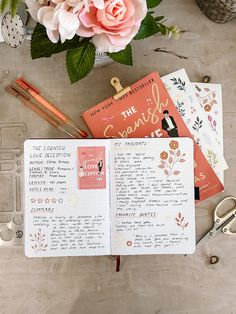 an open notebook sitting on top of a table next to flowers