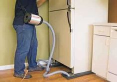 a man is using a vacuum to clean the refrigerator