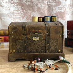 an old trunk with beads on the floor next to books and other items in front of it