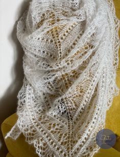 a white lace shawl sitting on top of a yellow chair