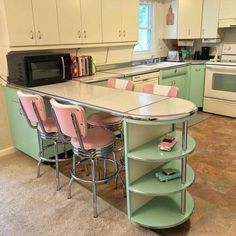 a kitchen with green cabinets and pink chairs