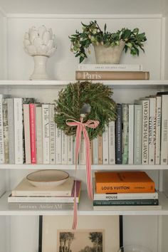 a book shelf with books and a wreath on top of it next to other books