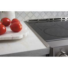 tomatoes are sitting on a cutting board next to an oven