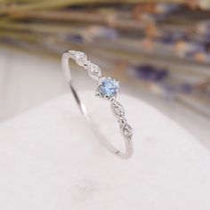 a white gold ring with a blue topazte and diamond accents on the band