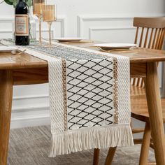 a table with a bottle of wine on top of it and a decorative runner in the middle