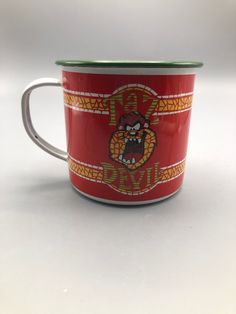 a red and green coffee cup sitting on top of a white table