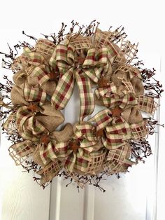 a burlock wreath on the front door is decorated with brown and green plaid ribbon