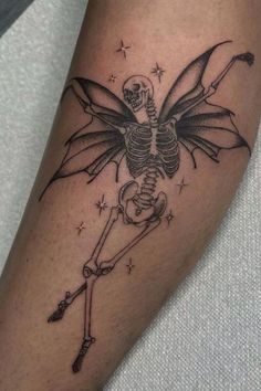 a skeleton with wings and a cross on its arm is shown in this tattoo design