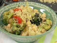 a green bowl filled with broccoli and chickpeas on top of a table