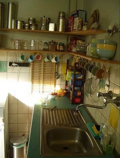 a kitchen with green counter tops and white tiled walls is pictured in this image, there are many dishes on the shelves above the sink