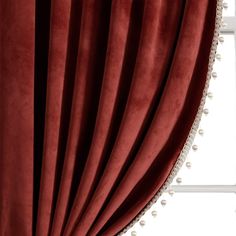 a red curtain with pearls hanging from it's side, in front of a window