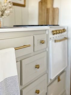 a kitchen with white cabinets and gold handles