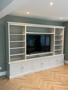 an empty entertainment center in a house with wood floors and gray walls, built - in bookshelves