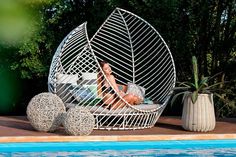 a woman sitting in a chair next to a pool with two balls on the ground