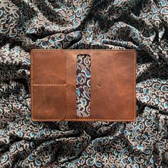 a brown leather wallet sitting on top of a blue and white cloth