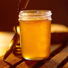 a jar filled with honey sitting on top of a wooden table next to a knife