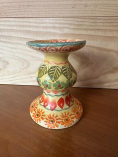 a colorful vase sitting on top of a wooden table