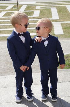 two little boys dressed in suits and sunglasses