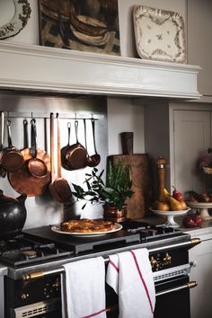 an oven with pots and pans hanging on it's wall next to other cooking utensils