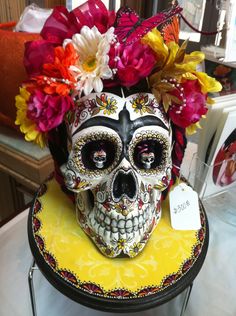 a skull with flowers in its hair sitting on a table