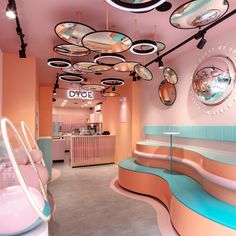 the interior of a pink and blue store with circular mirrors hanging from the ceiling above