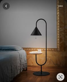 a lamp that is sitting on a table next to a bed in a room with wood flooring