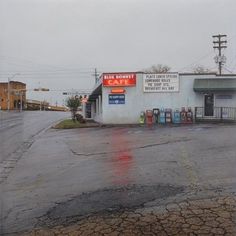 an empty parking lot in front of a gas station on a rainy, overcast day