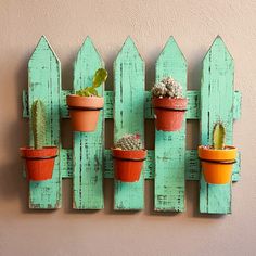 three small potted plants are mounted to a wooden fence with succulents in them