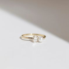 a close up of a ring with a pearl on the bottom and a diamond in the middle