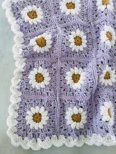 a crocheted blanket with white and yellow flowers