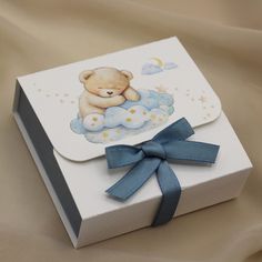 a white box with a blue ribbon and a teddy bear on it