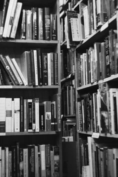 black and white photo of bookshelves full of different types of books in a library