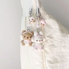 two small teddy bears are attached to a keychain on a white cloth background