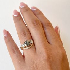 a woman's hand with a ring on top of it and an oval shaped diamond in the middle