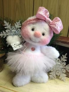 a white teddy bear wearing a pink hat and tutu with snowflakes around it