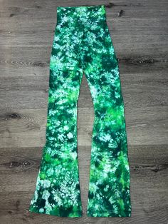 the green and white tie dye bell bottoms are shown on a wooden floor with wood planks in the background