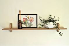 a wooden shelf with some plants on it and a framed photograph above the shelf, along with other items