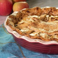 an apple pie sitting on top of a table next to apples