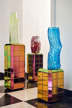 three colorful vases sitting on top of a checkered floor