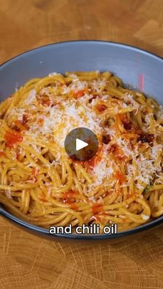 a bowl filled with spaghetti and sauce on top of a wooden table