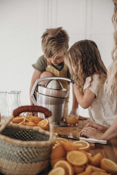 two children are looking at orange slices on the table while an older woman stands next to them