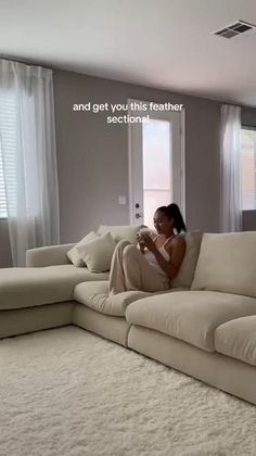 a woman sitting on top of a couch in a living room next to a window