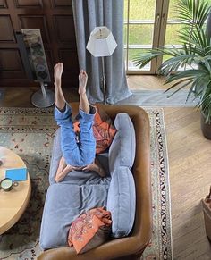 a man laying on top of a couch in a living room next to a window