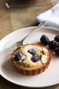 a small pastry on a plate with berries and almonds