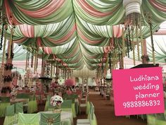 the inside of a wedding venue with green and pink chairs, tables and chandeliers