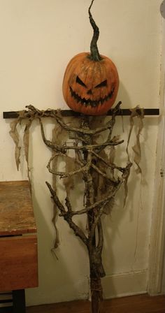 a pumpkin sitting on top of a tree branch in front of a wall with branches around it