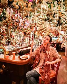 a woman sitting at a bar with lots of christmas decorations hanging from the ceiling above her