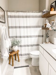 a bathroom with a white toilet sitting next to a bath tub under a shower curtain