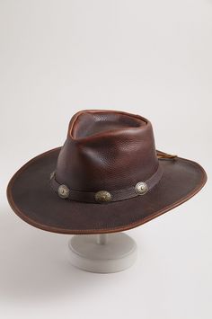 If ever there were a leather hat to handle the job, the strapless Raging Bull would be it. Made of rich, full-grain cowhide leather, this rugged hat is wonderfully durable, featuring a smooth hand, thick body, and superb protection from the elements. A tied hatband adorned with five conchos adds western appeal, while a cushioned sweatband keeps you cool and comfy in the heat of the moment. Luxury Adjustable Leather Cowboy Hat, Fitted Leather Hats For Western-themed Events, Rustic Leather Fedora For Western-themed Events, Luxury Leather Country Cowboy Hat, Preown Western Hats Gambler, Leather Cowboy Hats, Raging Bull, Leather Hats, Beautiful Hats