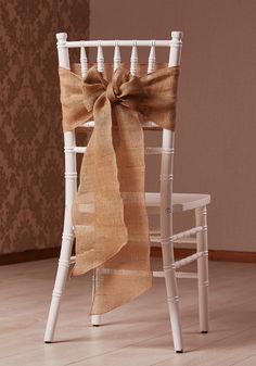 a white chair with a brown bow tied to it's back in front of a wall